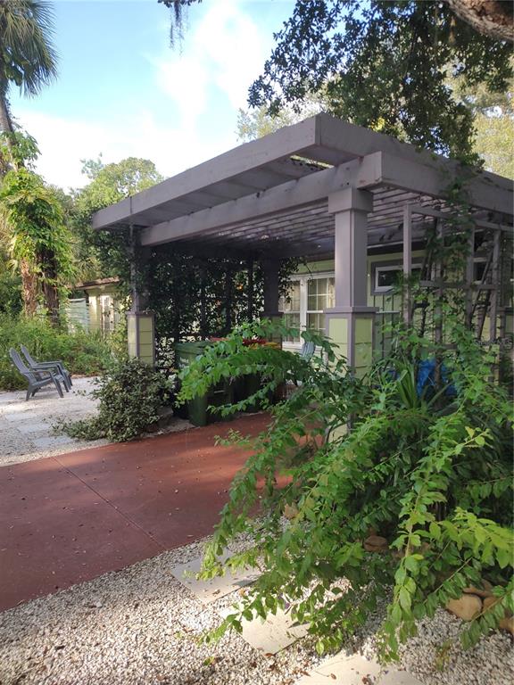 A wooden pergola covers a patio area next to a house with light green siding — 3400 CLARK DRIVE, SARASOTA, FL