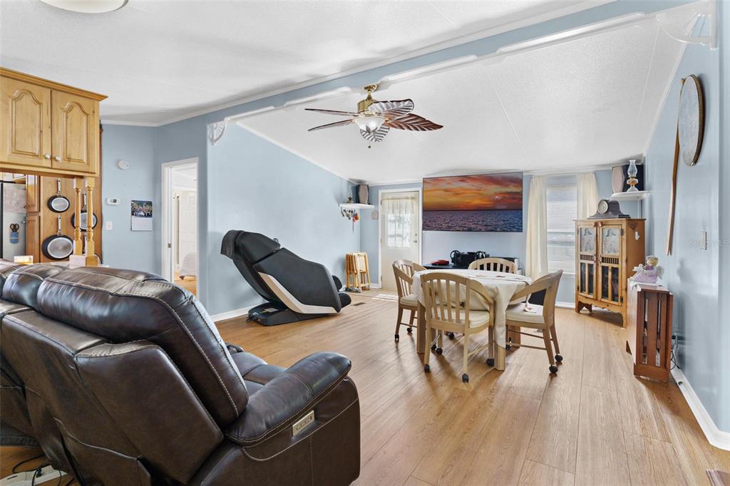 A living and dining area with light blue walls, wood-look flooring, and a ceiling fan — 12221 HELENA COURT, LEESBURG, FL