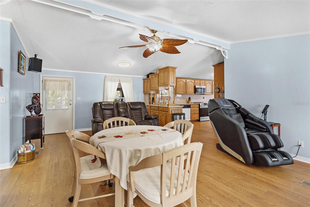 An open-concept living and dining area features light blue walls, wood flooring, and wooden cabinets — 12221 HELENA COURT, LEESBURG, FL