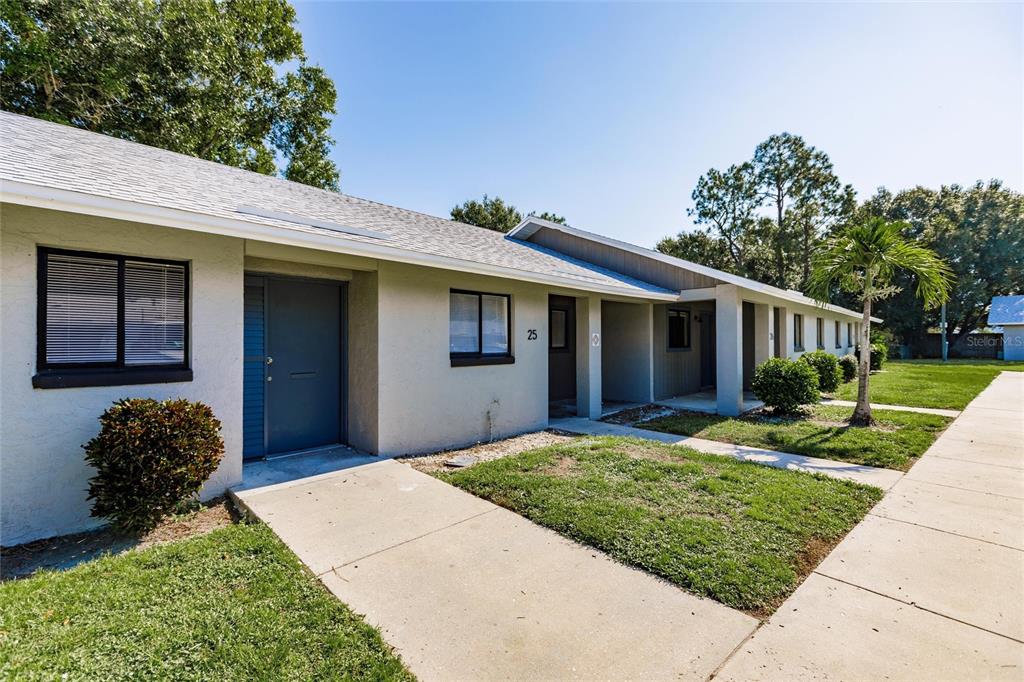 A single-story apartment building exterior features a gray facade, dark doors, and a concrete walkway — 1450 E GIBSON STREET, ARCADIA, FL