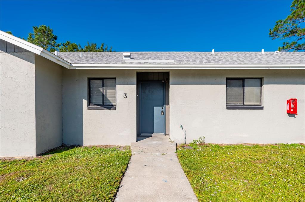 The exterior of a single-story building features a gray door marked with the number three — 1450 E GIBSON STREET, ARCADIA, FL