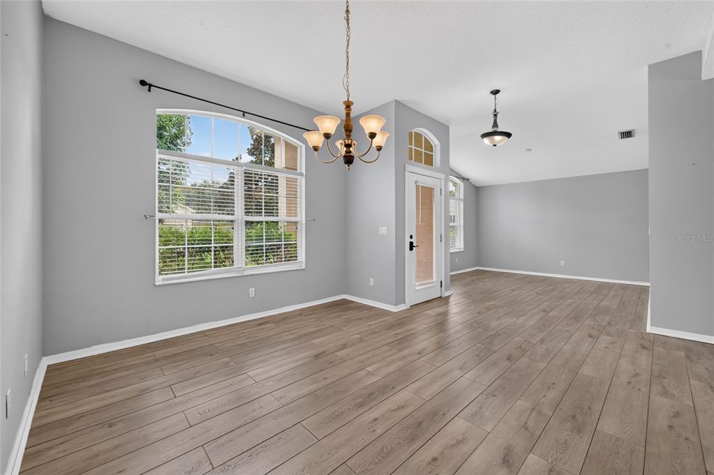 A dining area with wood-look flooring, gray walls, a chandelier, and a glass-paneled door — 8 BLACK WATER WAY, ORMOND BEACH, FL