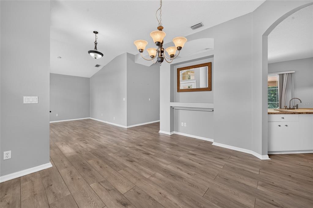A dining area with wood-look flooring, a chandelier, and a recessed wall niche with a mirror — 8 BLACK WATER WAY, ORMOND BEACH, FL