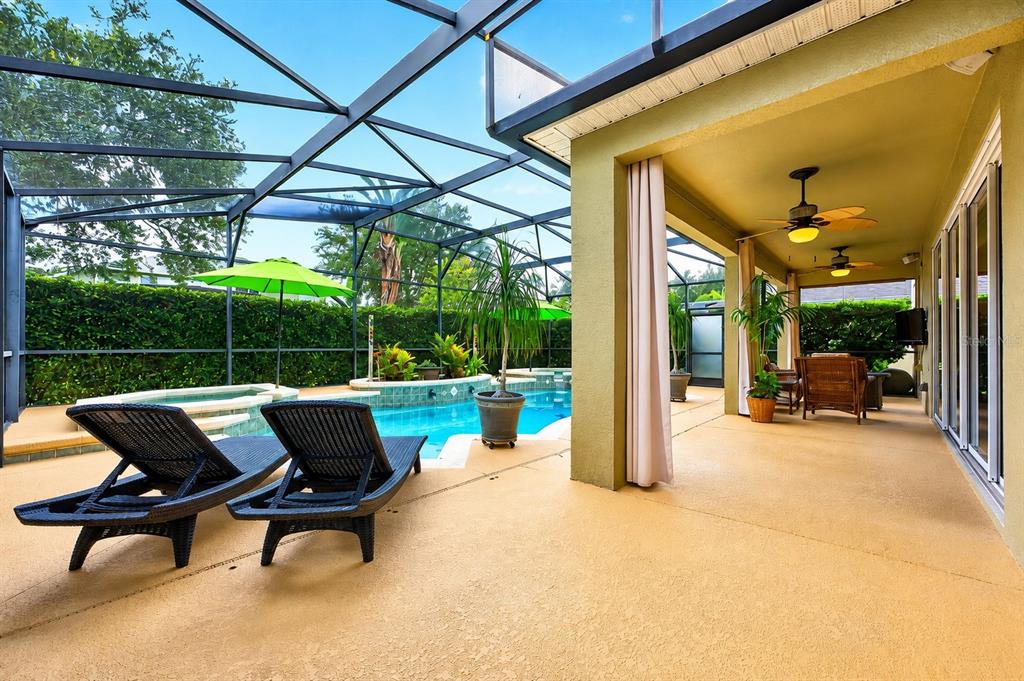 A covered patio features a ceiling fan, wicker furniture, a potted plant, and sliding glass doors — 10020 RUSTIC RIDGE COURT, ORLANDO, FL