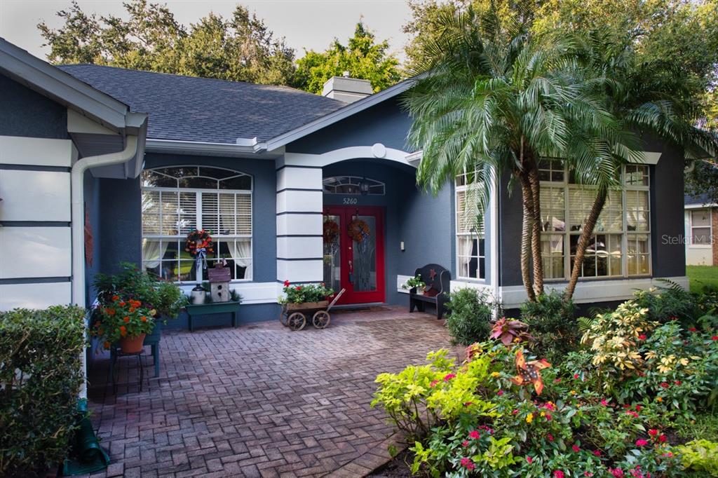 The exterior of a blue house features a red front door and a brick patio — 5260 HAMMOCK CIRCLE, ST CLOUD, FL