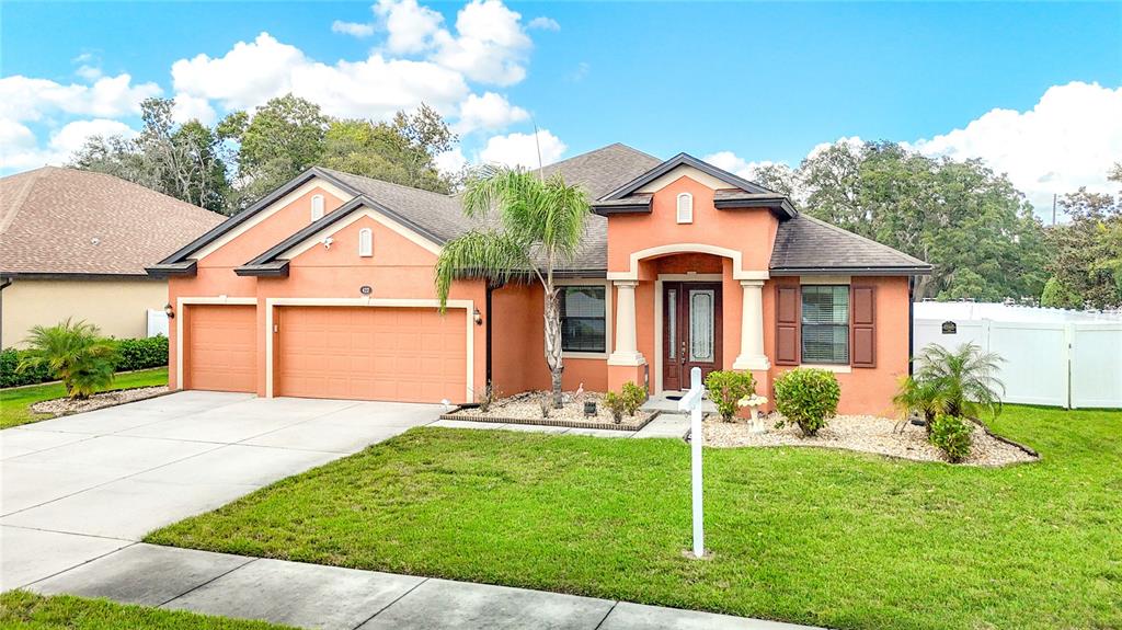 A single-story house with a peach-colored exterior, a three-car garage, and a front lawn — 422 CHALLICE DRIVE, SPRING HILL, FL