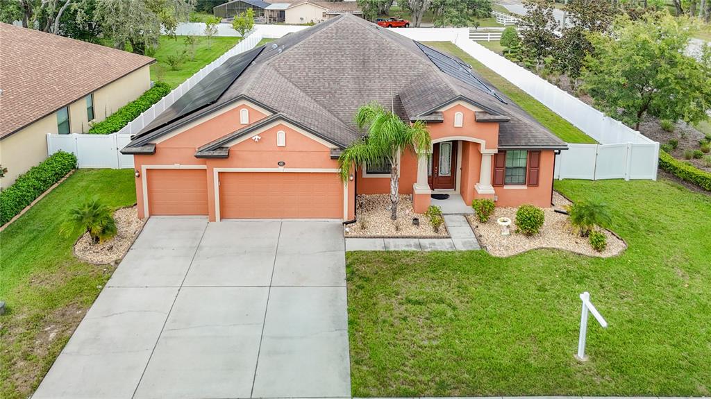 An aerial view of a single-story peach-colored house with a garage and solar panels — 422 CHALLICE DRIVE, SPRING HILL, FL