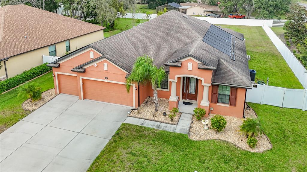 An aerial view of a single-story orange stucco house with a garage and solar panels — 422 CHALLICE DRIVE, SPRING HILL, FL