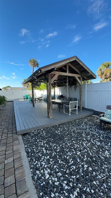 A wooden pavilion sits on a gray deck in a backyard with a gravel area — 108 5TH ST SO UNIT 2B, FLAGLER BEACH, FL
