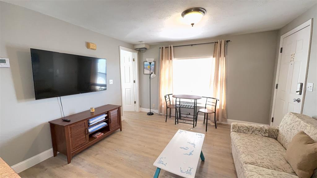 A living room features a television, media console, small dining table, and a patterned sofa — 108 5TH ST SO UNIT 2B, FLAGLER BEACH, FL