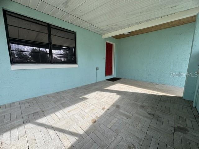 A covered patio features light blue stucco walls, a red door, and gray paver flooring — 508 PARK DRIVE, BABSON PARK, FL