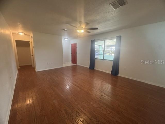 An empty living room features hardwood floors, a ceiling fan, and a red front door — 508 PARK DRIVE, BABSON PARK, FL