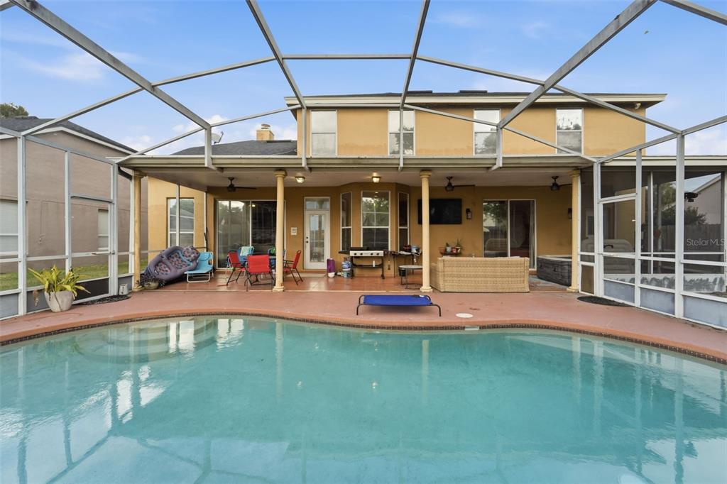 A backyard swimming pool with a screened-in patio and a two-story tan house exterior — 3874 GATLIN PLACE CIRCLE, ORLANDO, FL