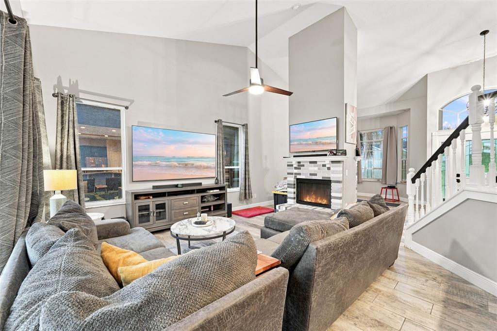 A living room features a fireplace, two televisions, gray sectional sofas, and vaulted ceilings — 3874 GATLIN PLACE CIRCLE, ORLANDO, FL