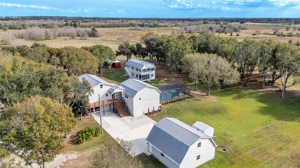 An aerial view shows a multi-building residential property with a pool and large yard — 13 BOGEY DRIVE, WINTER HAVEN, FL