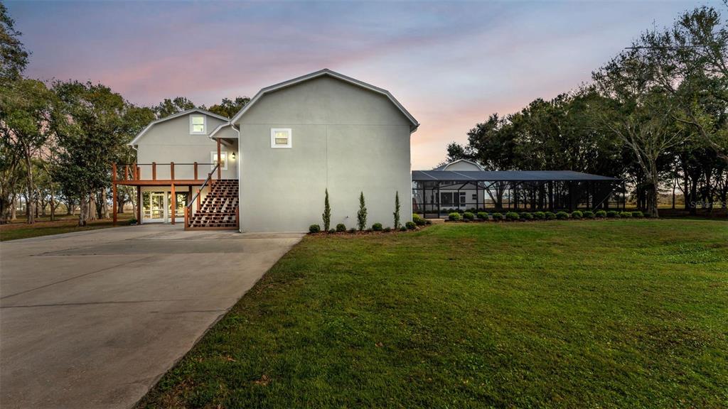 A two-story house with a concrete driveway, wooden deck, and a screened-in patio area — 13 BOGEY DRIVE, WINTER HAVEN, FL