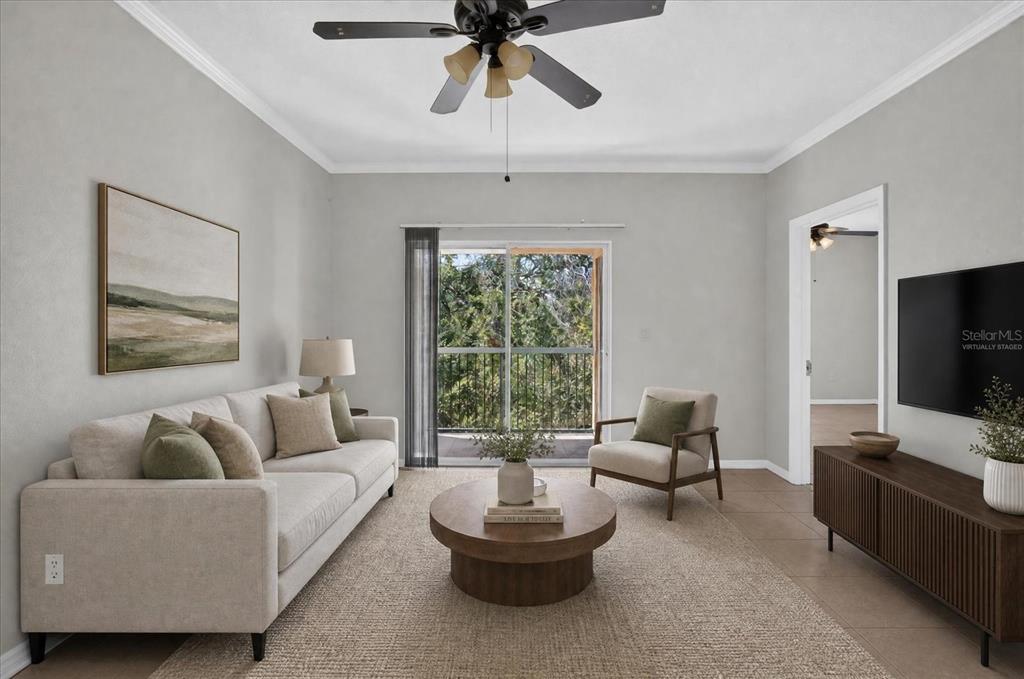 A living room with a sofa, armchair, coffee table, television, and a sliding glass door — 5608 PINNACLE HEIGHTS CIRCLE UNIT 305, TAMPA, FL