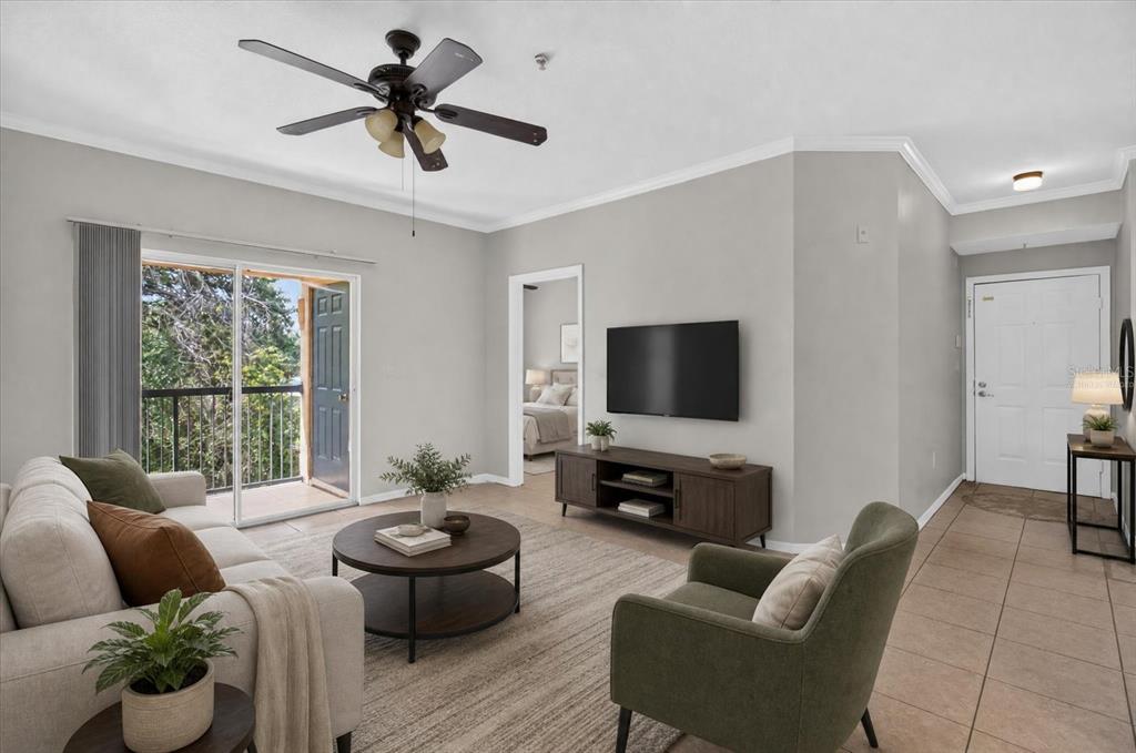 A living room with a sofa, armchair, coffee table, television, and a sliding glass balcony door — 5608 PINNACLE HEIGHTS CIRCLE UNIT 305, TAMPA, FL