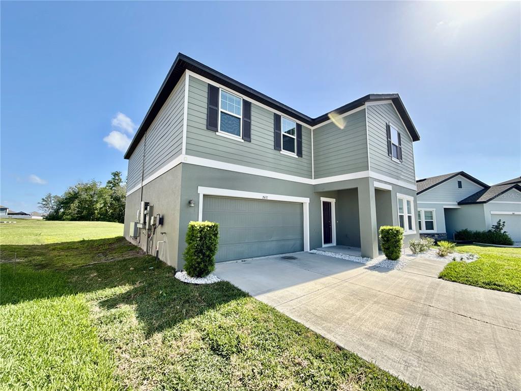 A two-story house with light green siding, a two-car garage, and a concrete driveway — 35657 BUTTONWEED TRAIL, ZEPHYRHILLS, FL