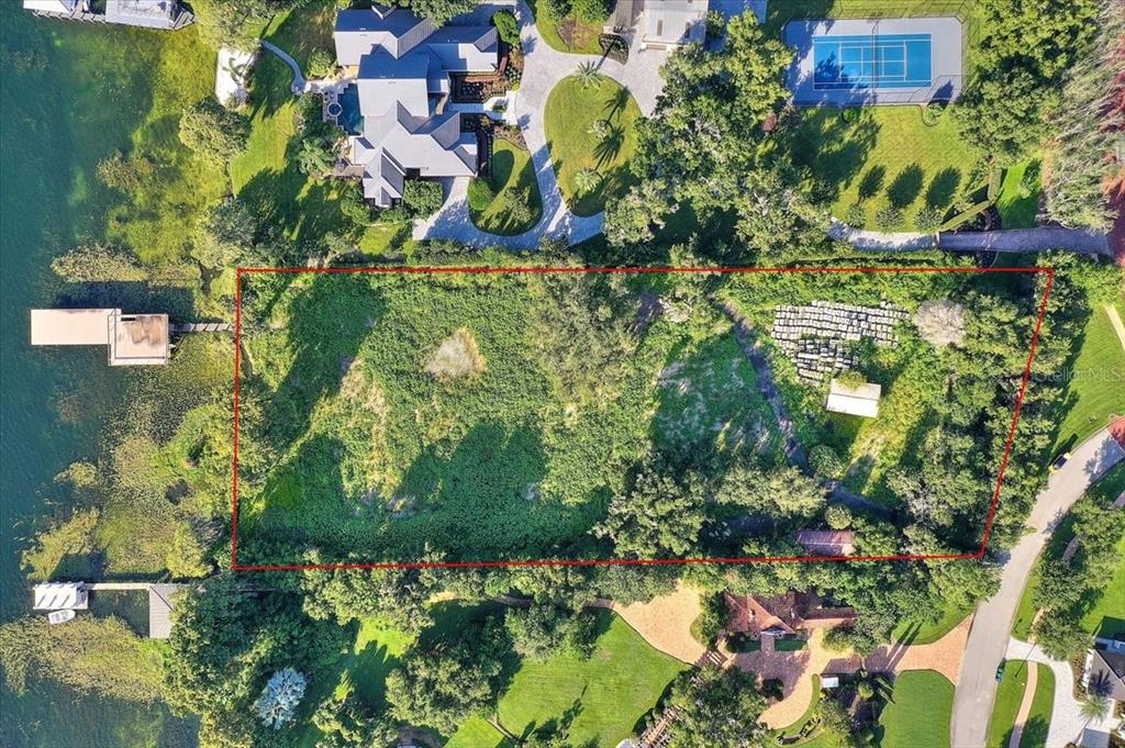 An aerial view shows a rectangular, tree-covered vacant lot situated between a lake and road — 12422 PARK AVENUE, WINDERMERE, FL