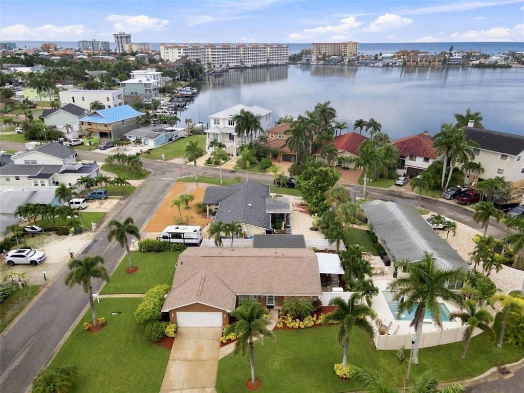 An aerial view shows a residential neighborhood with a house featuring a pool and palm trees — 28 WALL TERRACE, REDINGTON SHORES, FL