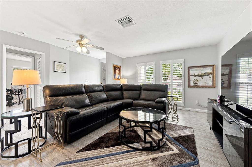 A living room features a black leather sectional, a glass coffee table, and tile flooring — 28 WALL TERRACE, REDINGTON SHORES, FL