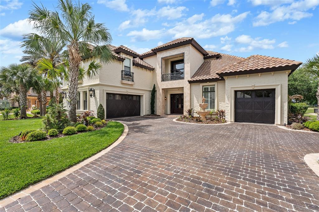A two-story stucco house with a tiled roof, a brick driveway, and two garage doors — 641 WOODBRIDGE DRIVE, ORMOND BEACH, FL