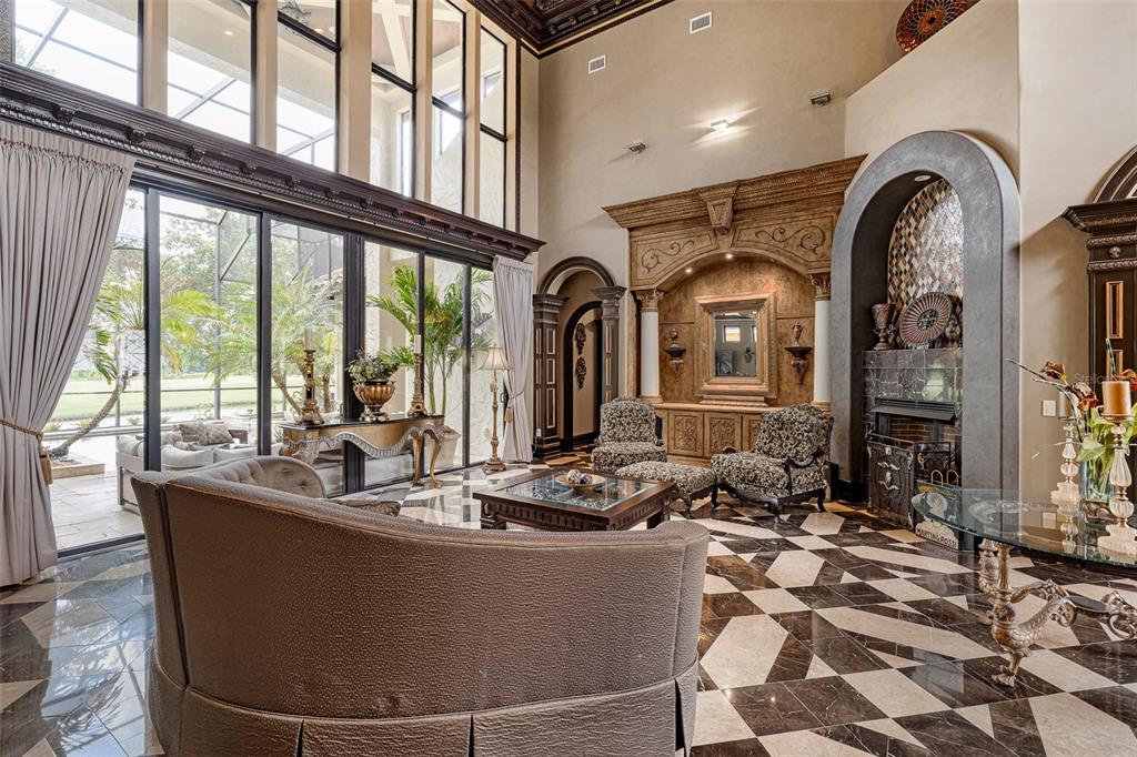 A spacious living room features high ceilings, floor-to-ceiling windows, a fireplace, and patterned marble floors — 641 WOODBRIDGE DRIVE, ORMOND BEACH, FL