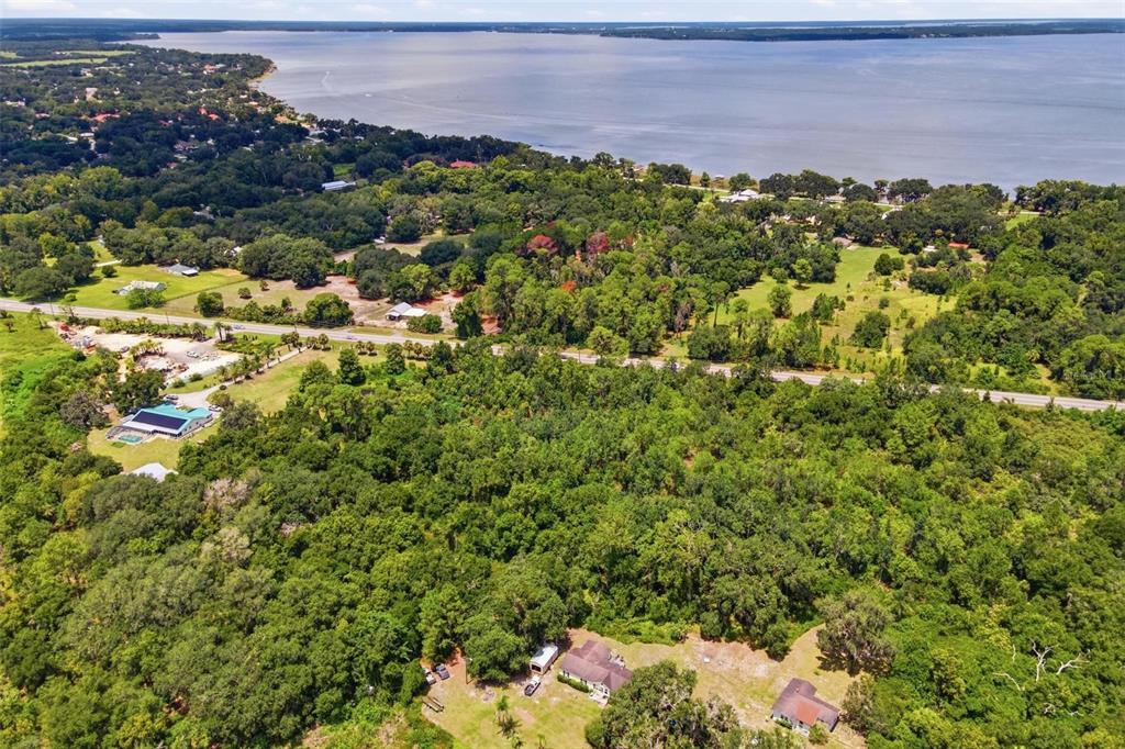 An aerial view shows a wooded landscape with houses, a road, and a large lake — COUNTY ROAD 48, YALAHA, FL