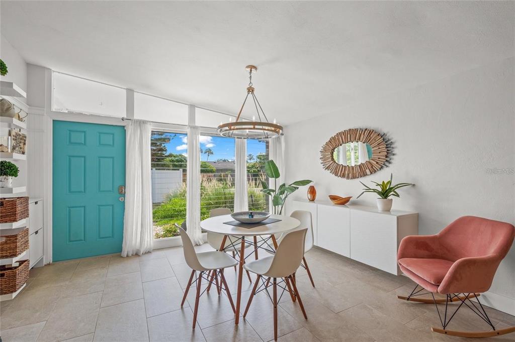 A dining room features a round table, white chairs, a teal door, and a rocking chair — 4801 SARASOTA AVENUE, SARASOTA, FL