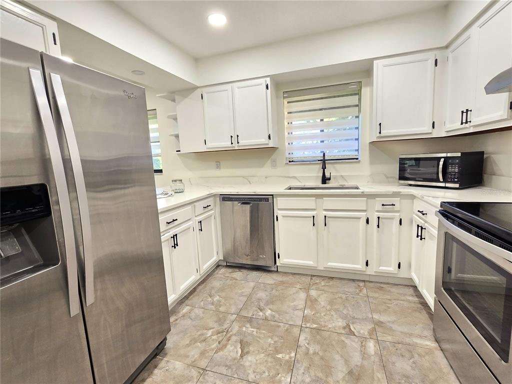 A kitchen with white cabinets, stainless steel appliances, and light-colored countertops — 2009 HAMMOCK PINE BOULEVARD UNIT 2009, CLEARWATER, FL