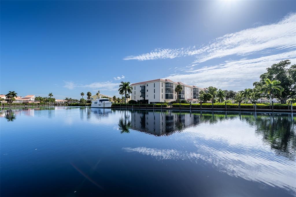 A multi-story apartment building stands beside a calm canal with a boat docked nearby — 25188 MARION AVENUE UNIT E104, PUNTA GORDA, FL