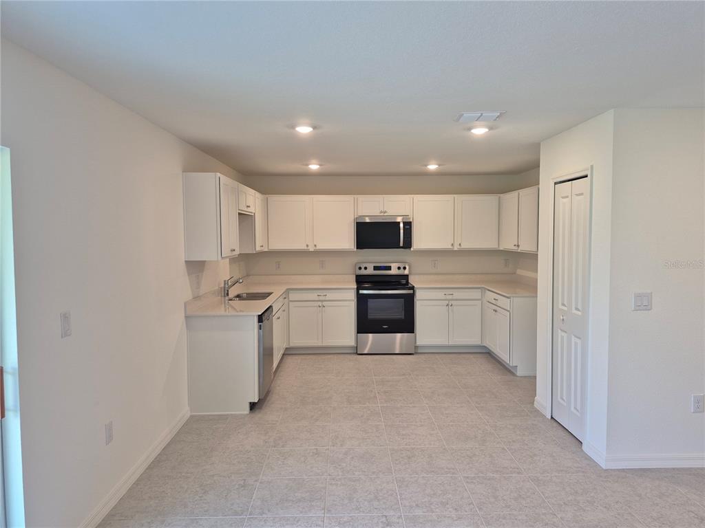 A bedroom with beige carpet, white walls, recessed lighting, and an attached bathroom — 8813 PINE BARK WAY, WILDWOOD, FL