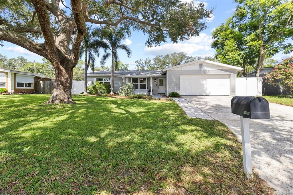 A single-story house with a two-car garage, a large oak tree, and a front lawn — 11290 116TH STREET, LARGO, FL