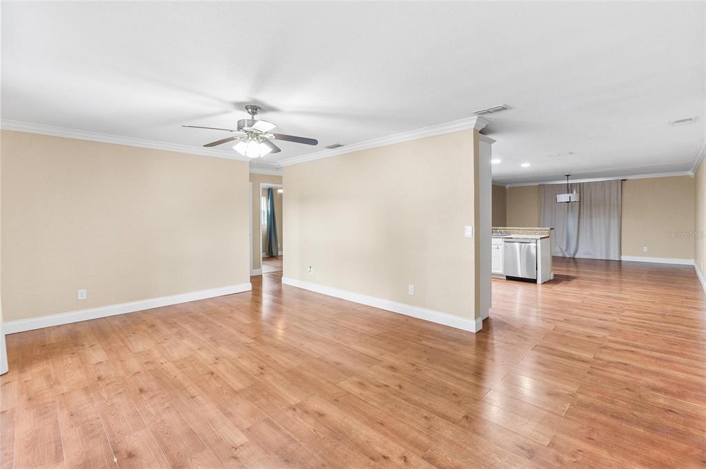 An open-concept living area features light-colored walls, wood-look flooring, and a ceiling fan — 11290 116TH STREET, LARGO, FL