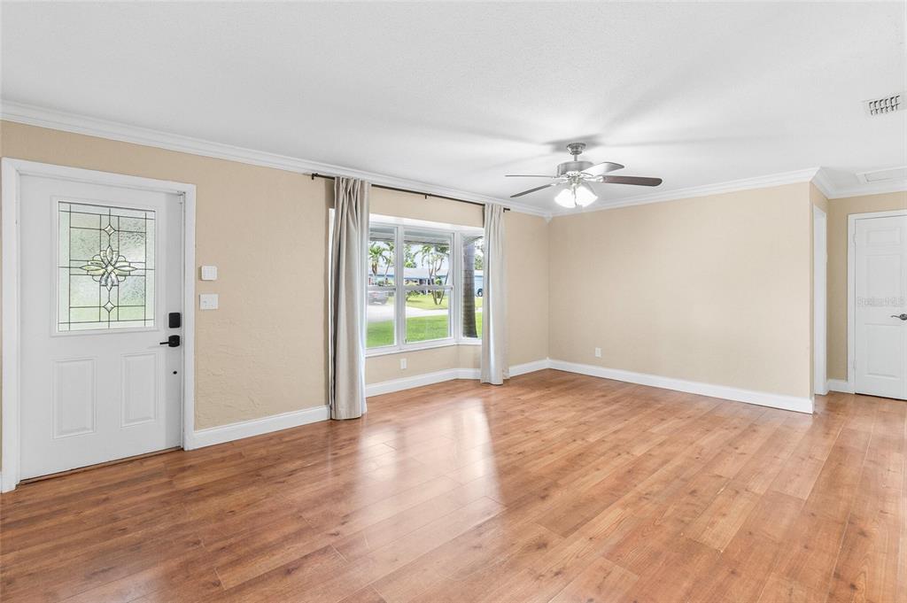 A living room with wood-look flooring, a ceiling fan, and a front door with glass — 11290 116TH STREET, LARGO, FL
