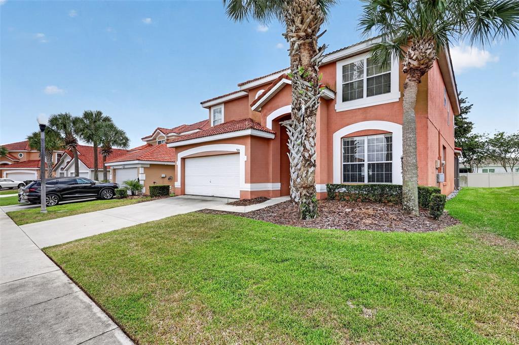 A two-story, orange stucco house with a white garage door and palm trees in front — 928 SOLANA CIRCLE, DAVENPORT, FL