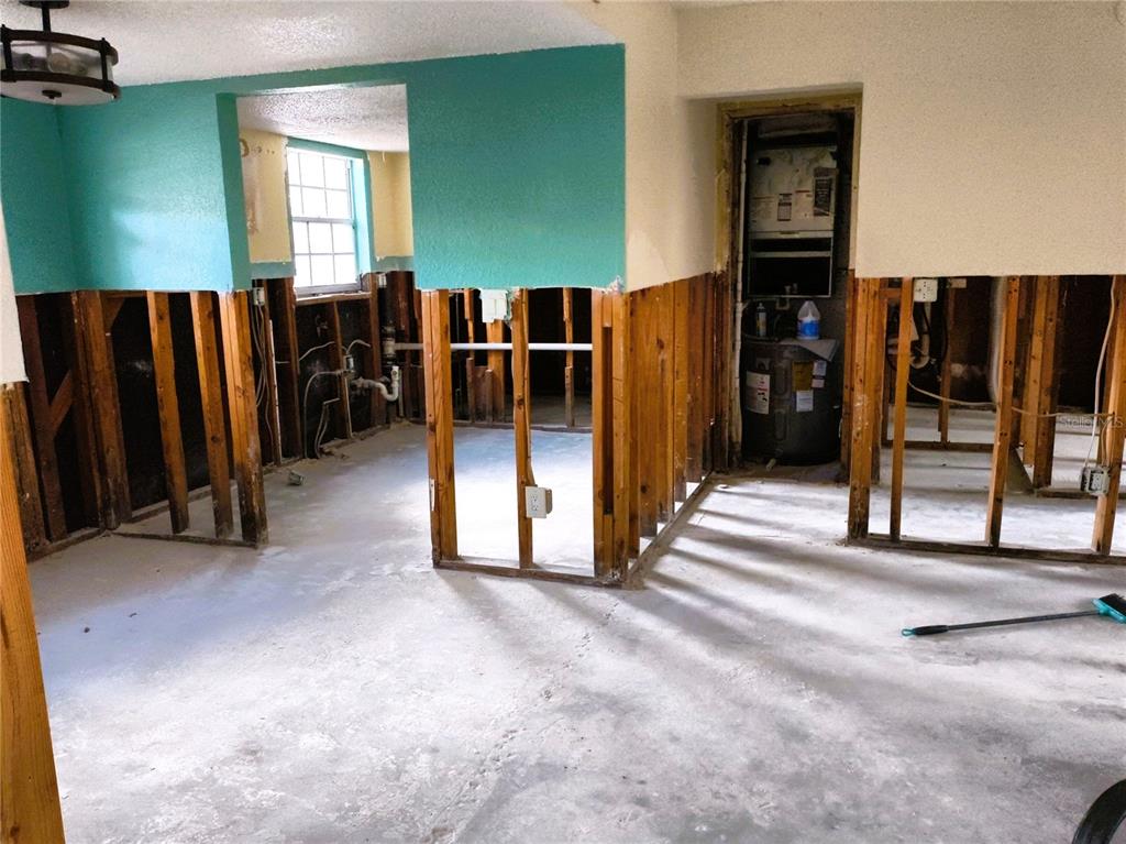 An interior room under renovation with exposed wall studs, concrete flooring, and a water heater — 200 COUNTRY CLUB DRIVE UNIT 805, LARGO, FL