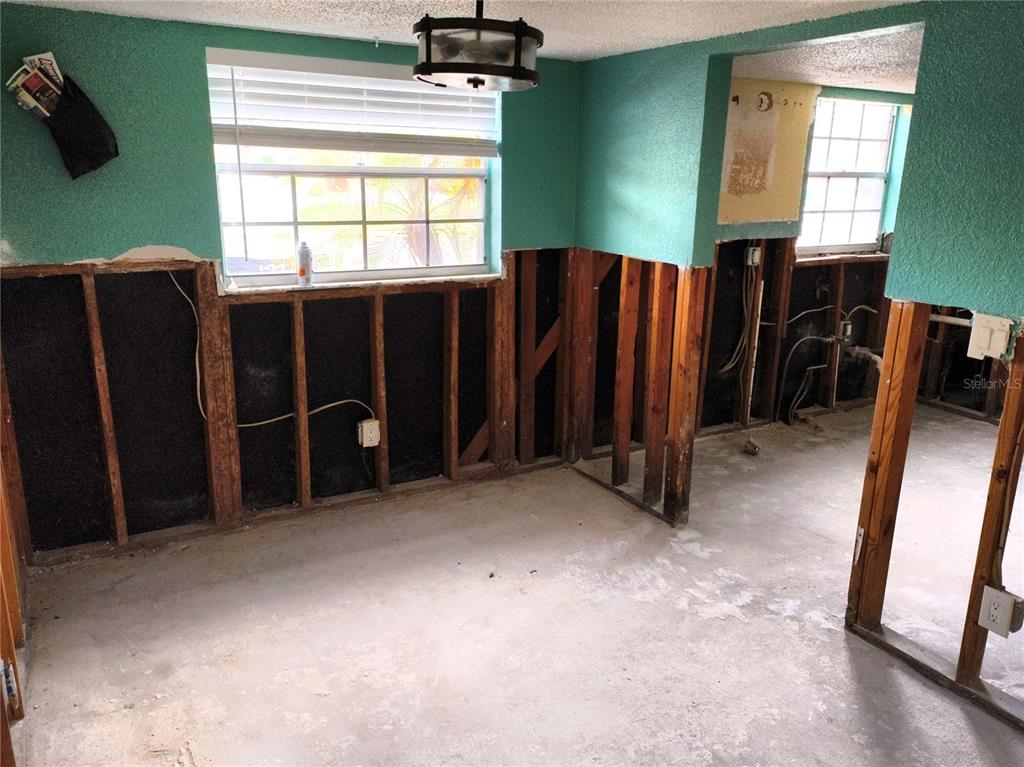 An unfinished room with exposed wall studs, concrete flooring, and teal-painted upper walls — 200 COUNTRY CLUB DRIVE UNIT 805, LARGO, FL