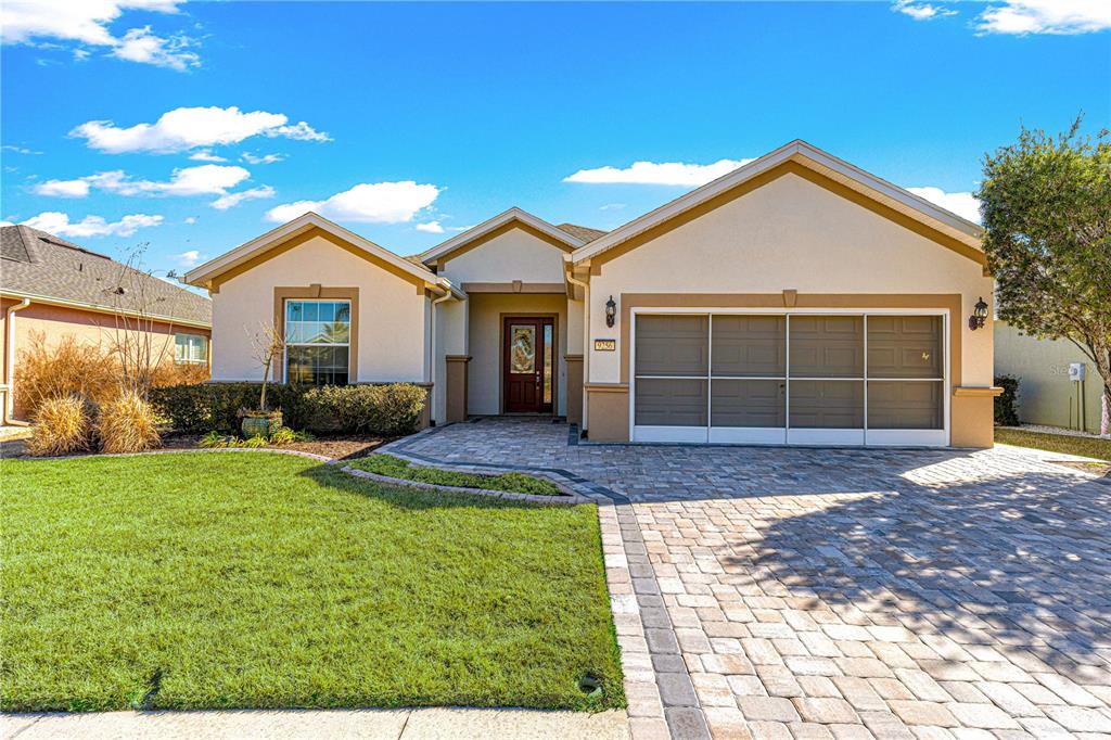 A single-story house with a beige stucco exterior, a paver driveway, and a two-car garage — 9256 SW 66TH LOOP, OCALA, FL