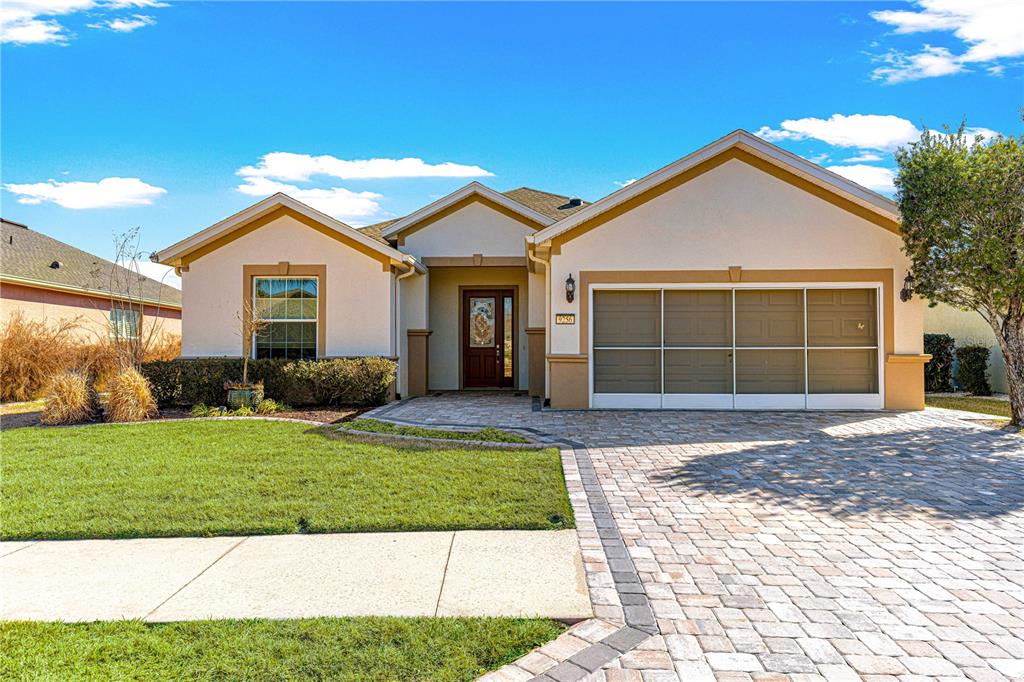 A single-story house with a beige stucco exterior, a paver driveway, and a two-car garage — 9256 SW 66TH LOOP, OCALA, FL