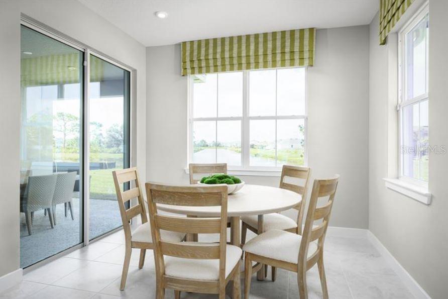 A dining area features a round table with four chairs, large windows, and sliding glass doors — 8343 WENDY ROSE WAY, LEESBURG, FL