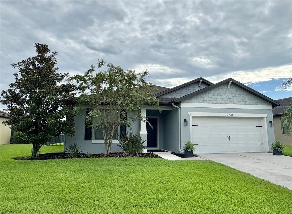 A single-story house with a light blue exterior, a two-car garage, and a front lawn — 9720 58TH STREET E, PARRISH, FL