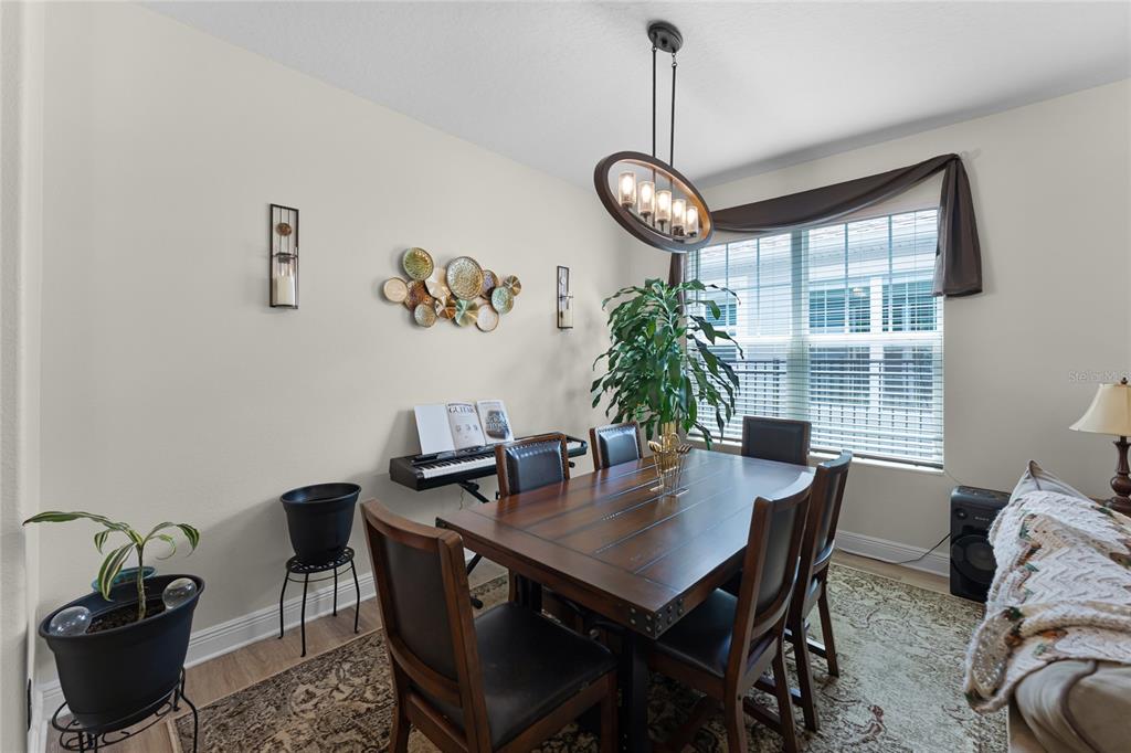A dining room features a dark wood table, six chairs, a chandelier, and wall decor — 4920 BLANCHE COURT, ST CLOUD, FL