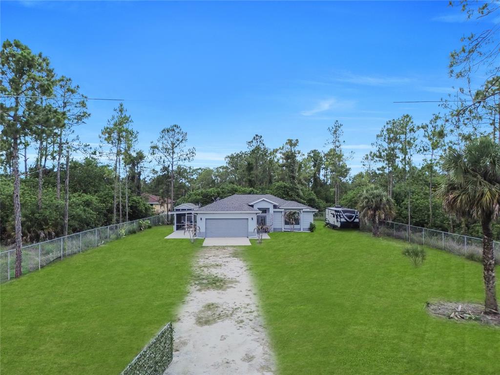 An aerial view shows a single-story house with a large lawn and a gravel driveway — 2021 HINES AVENUE, ALVA, FL