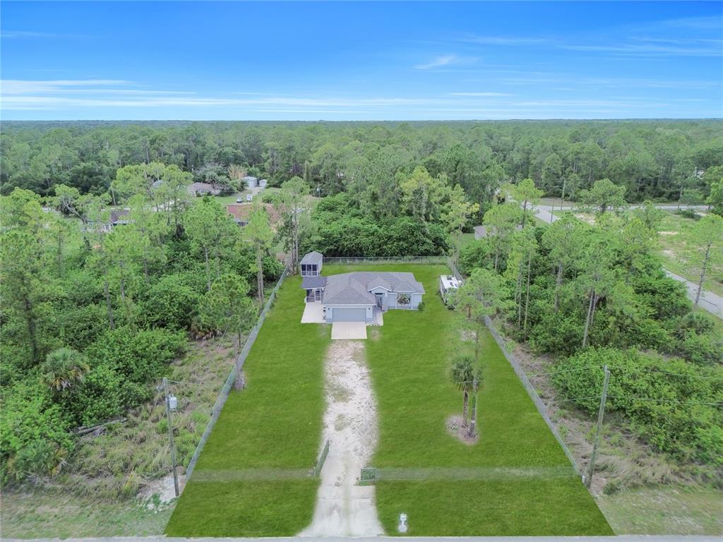 An aerial view shows a single-story house with a long driveway on a wooded lot — 2021 HINES AVENUE, ALVA, FL