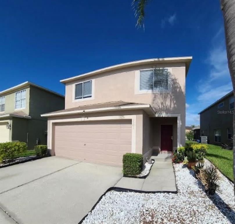 A two-story house with a beige stucco exterior, a two-car garage, and a red door — 1501 RINCON DRIVE, WESLEY CHAPEL, FL