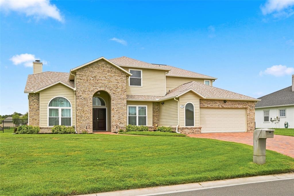 A two-story house with tan siding, a stone facade, and an attached two-car garage — 1791 LISA LANE, KISSIMMEE, FL