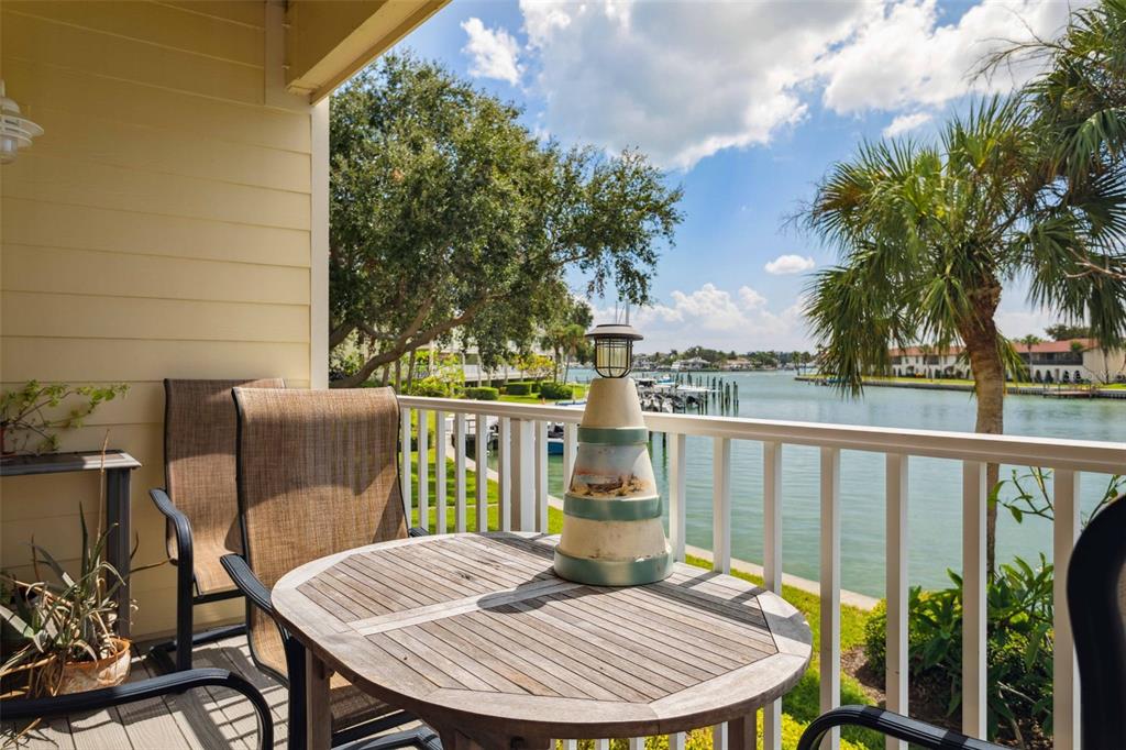 A balcony with a wooden table, chairs, and a lighthouse decoration overlooking a waterfront canal — 459 HAVEN POINT DRIVE, TREASURE ISLAND, FL