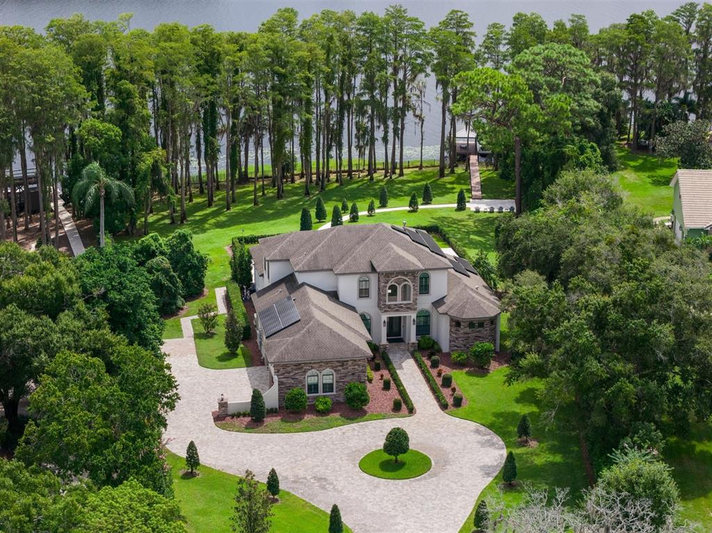 An aerial view shows a large house with a stone facade and circular driveway — 9412 EDDINGS ROAD, ODESSA, FL